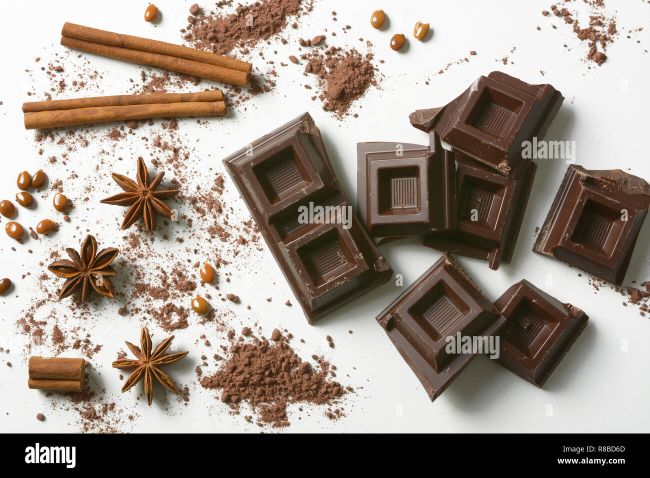 Pezzi di cioccolato, cannella, anice stellato e cacao in polvere sullo sfondo bianco - primo piano Foto Stock