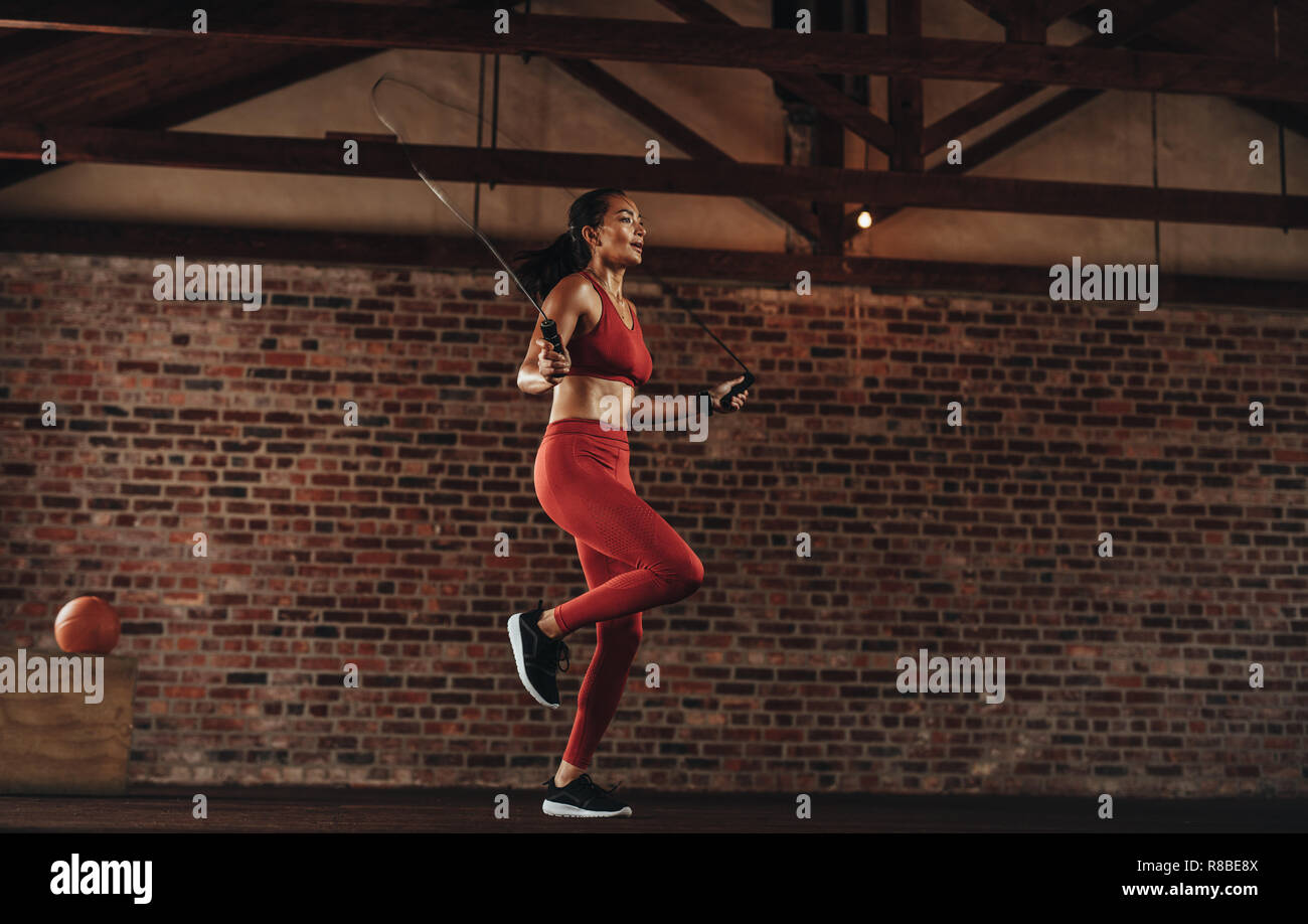 Donna sana esercitando con corda da salto a fitness studio. Sportive facendo saltare la corda allenamento in palestra. Foto Stock
