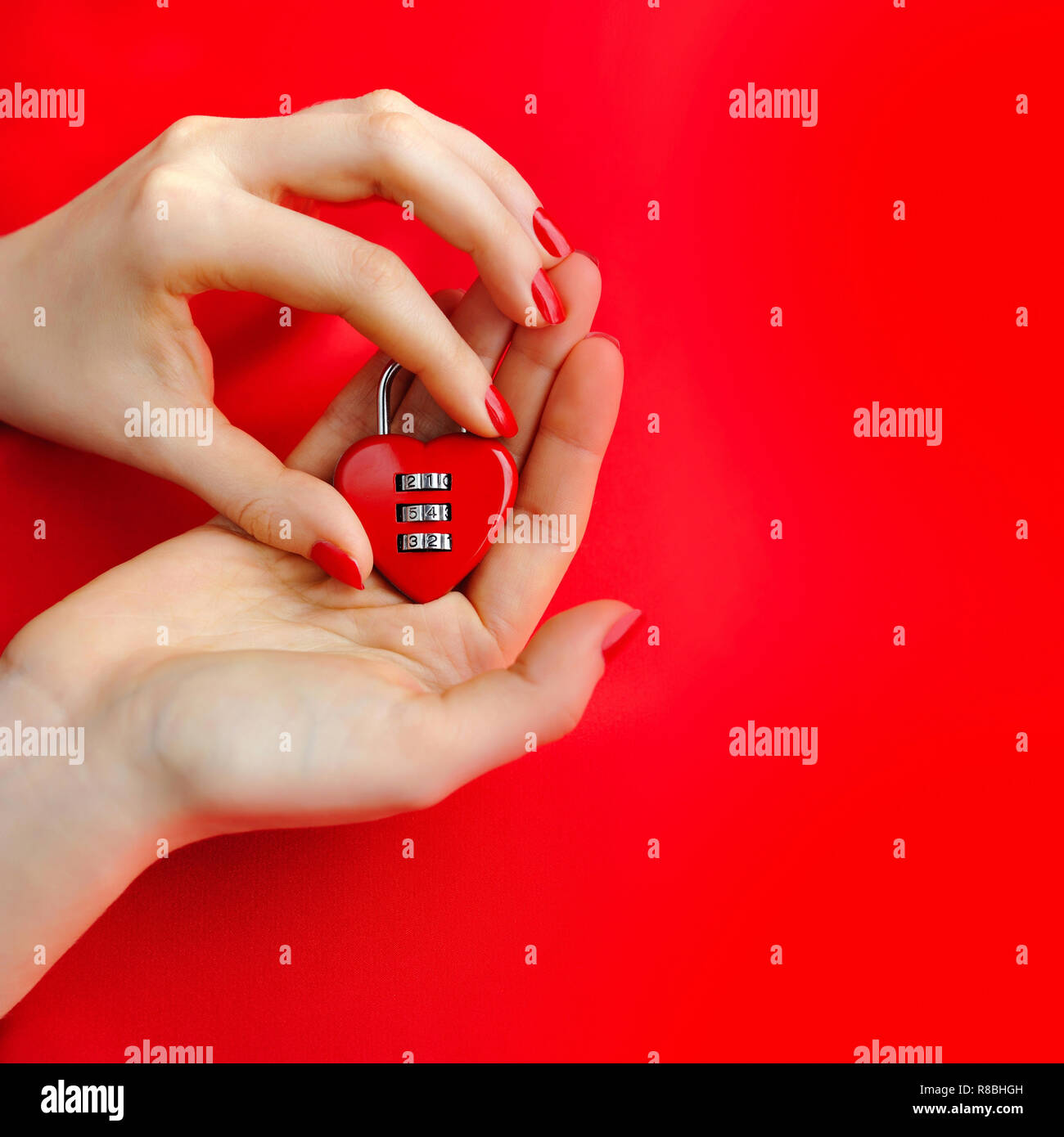 Lucchetto a cuore in forma le mani delle donne su sfondo rosso Foto Stock