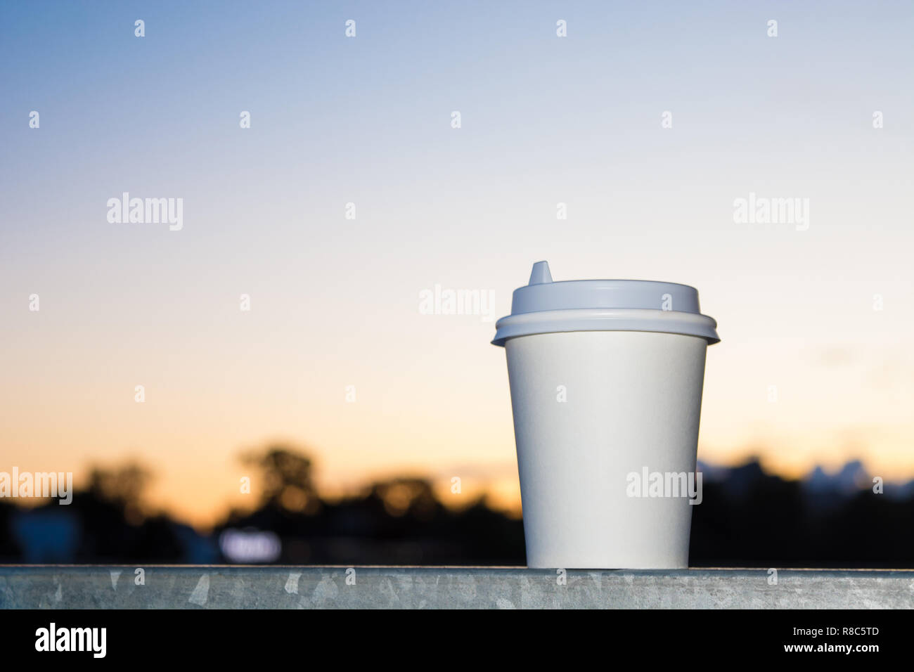 Caffè di andare in carta bianca cup in città urbana con il tramonto del sole Foto Stock