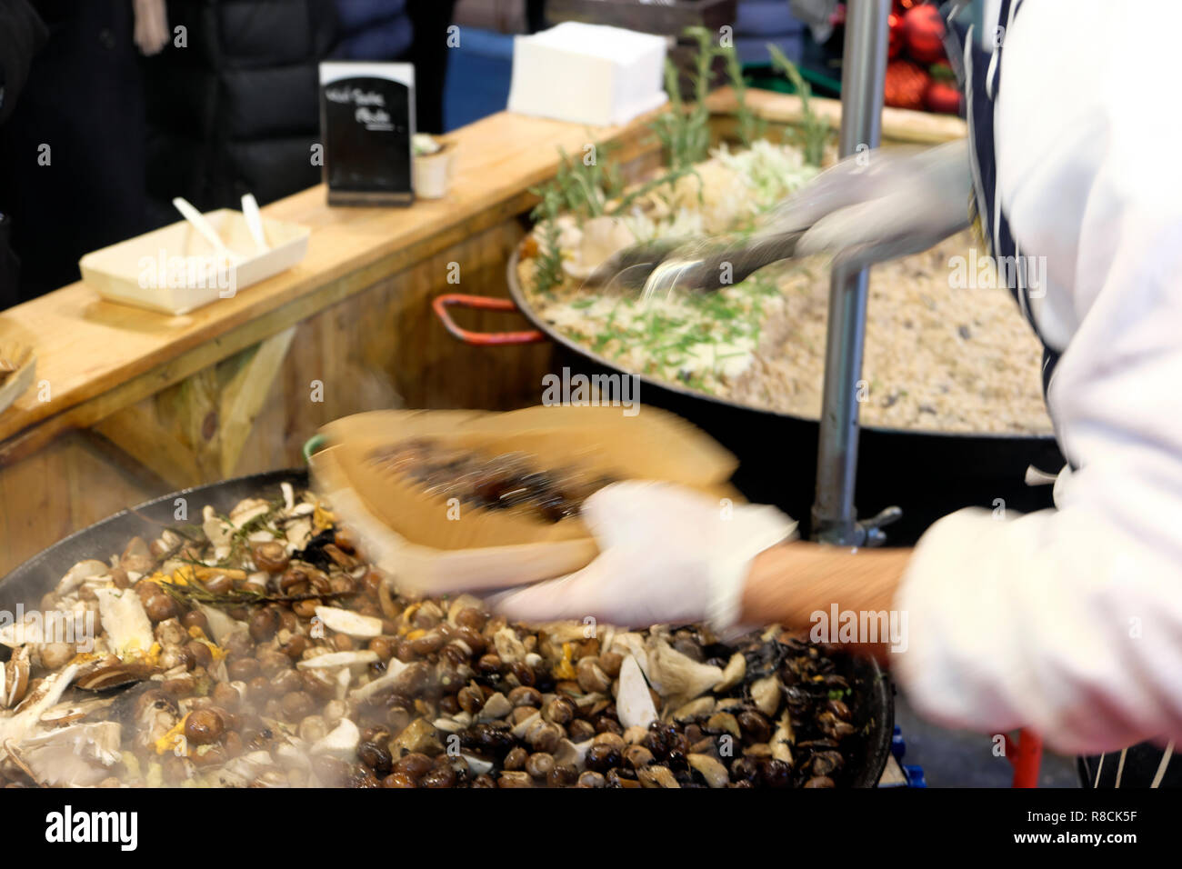 Un cuoco italiano a caldo di cottura di funghi selvatici risotto di farro in un mercato di Borough stallo nella parte sud di Londra Inghilterra REGNO UNITO KATHY DEWITT Foto Stock