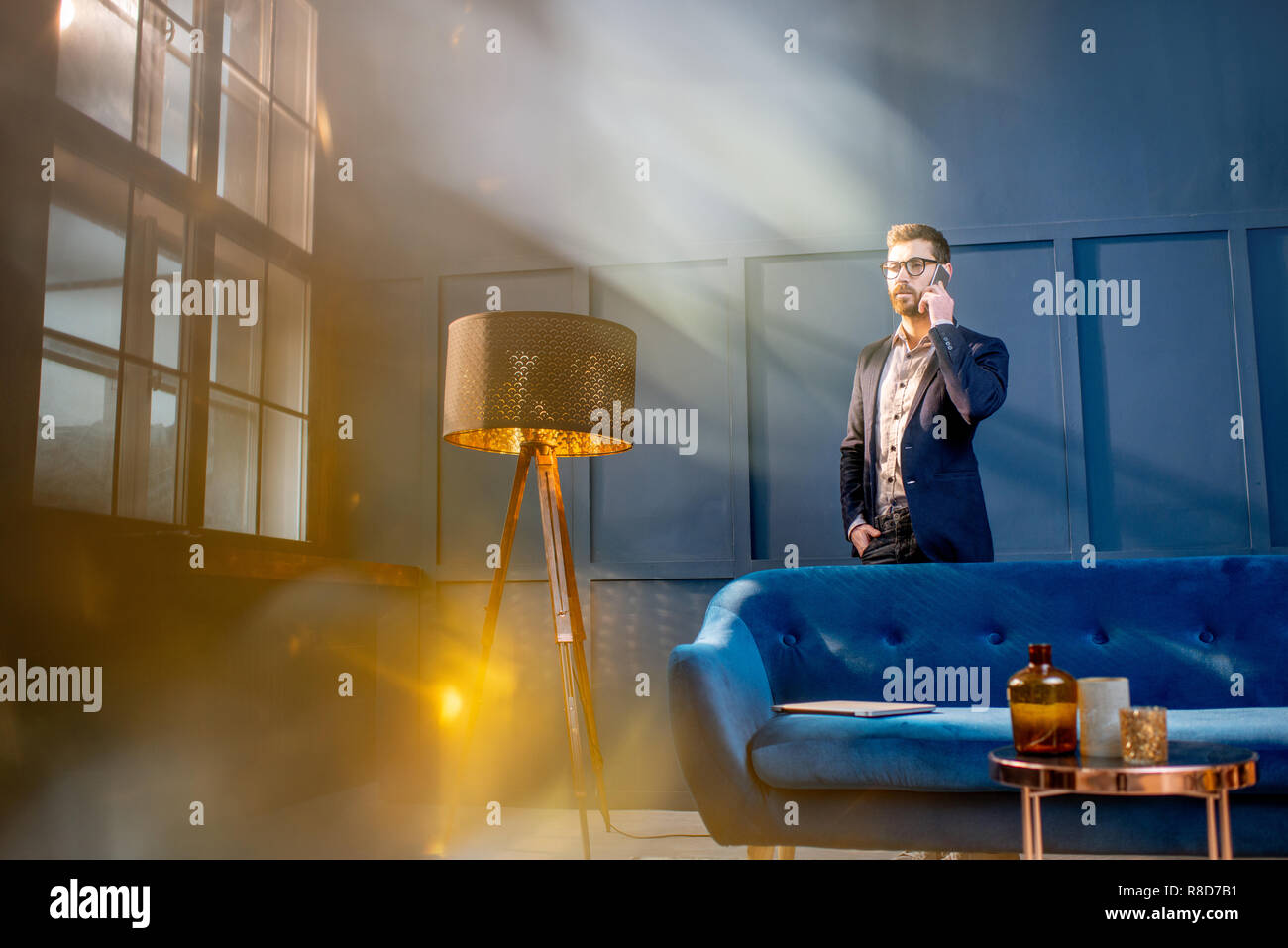Ritratto di un imprenditore elegante seduta con il computer portatile sul lettino al lusso ufficio blu interno Foto Stock