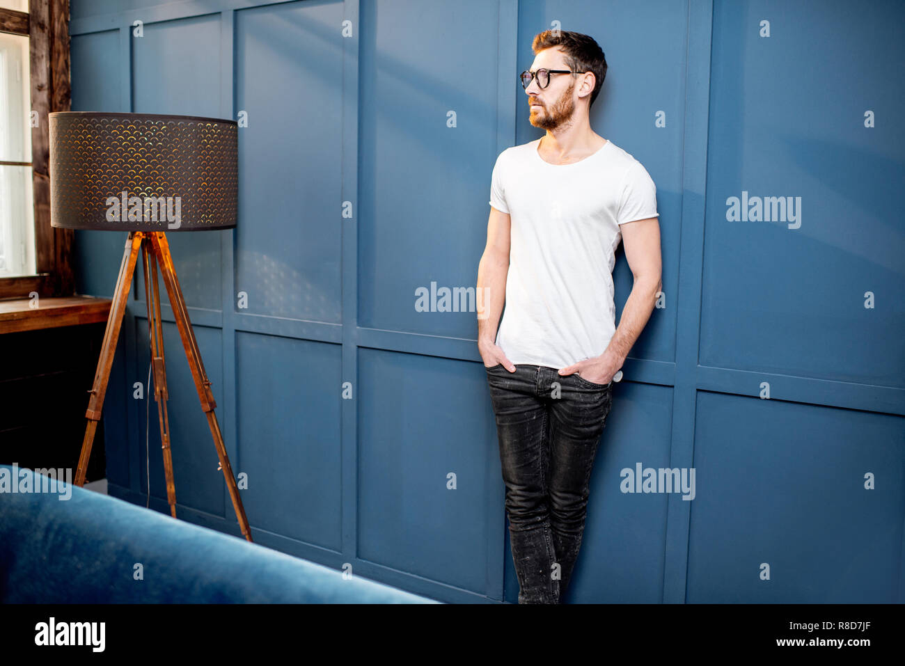 Ritratto di un uomo in bianco t-shirt in piedi sulla parete blu sullo sfondo nella casa di lusso o office intreior Foto Stock