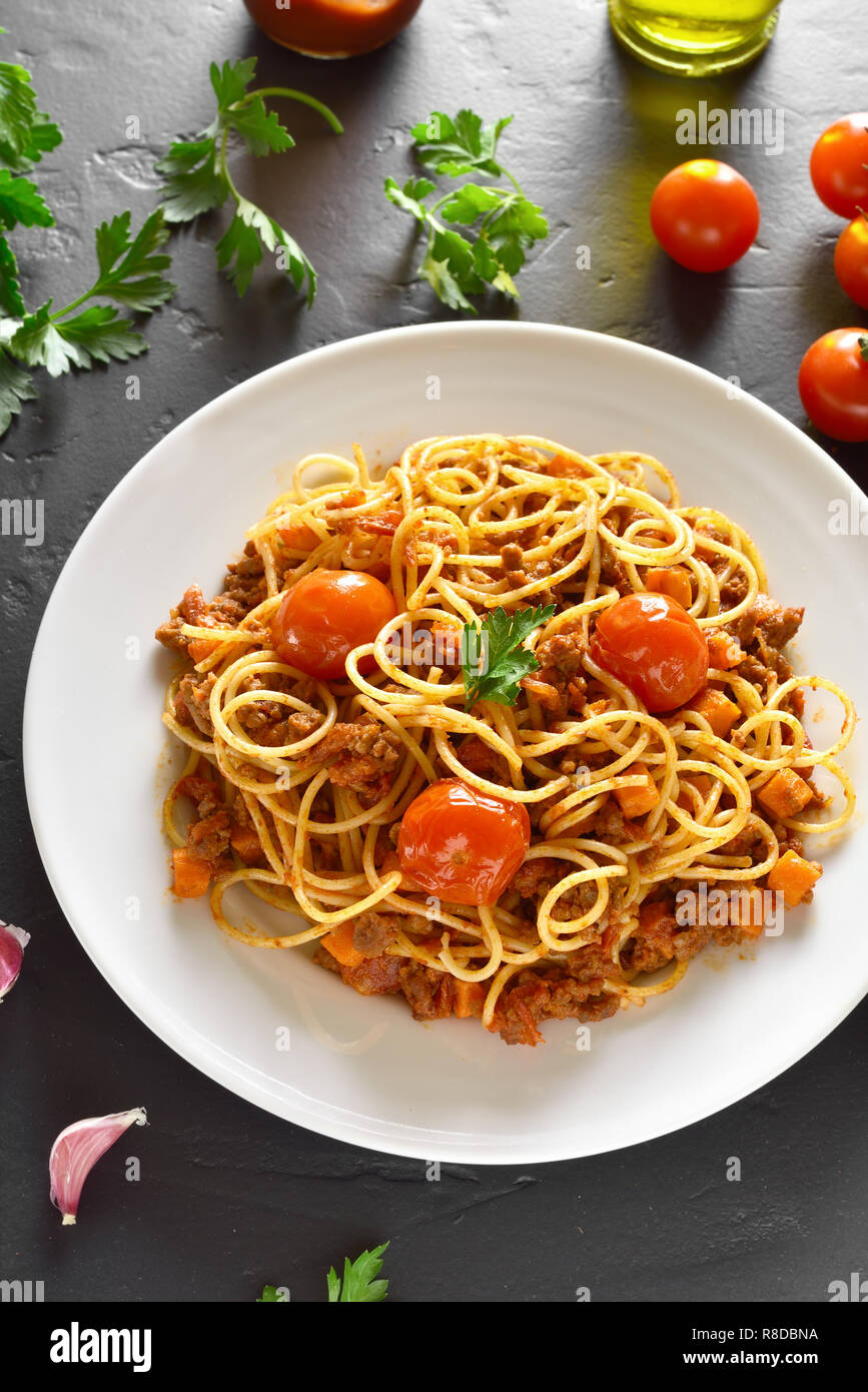 Piatto per la cena. Spaghetti alla bolognese con carne tritata e pomodori ciliegia sulla pietra nera tabella Foto Stock