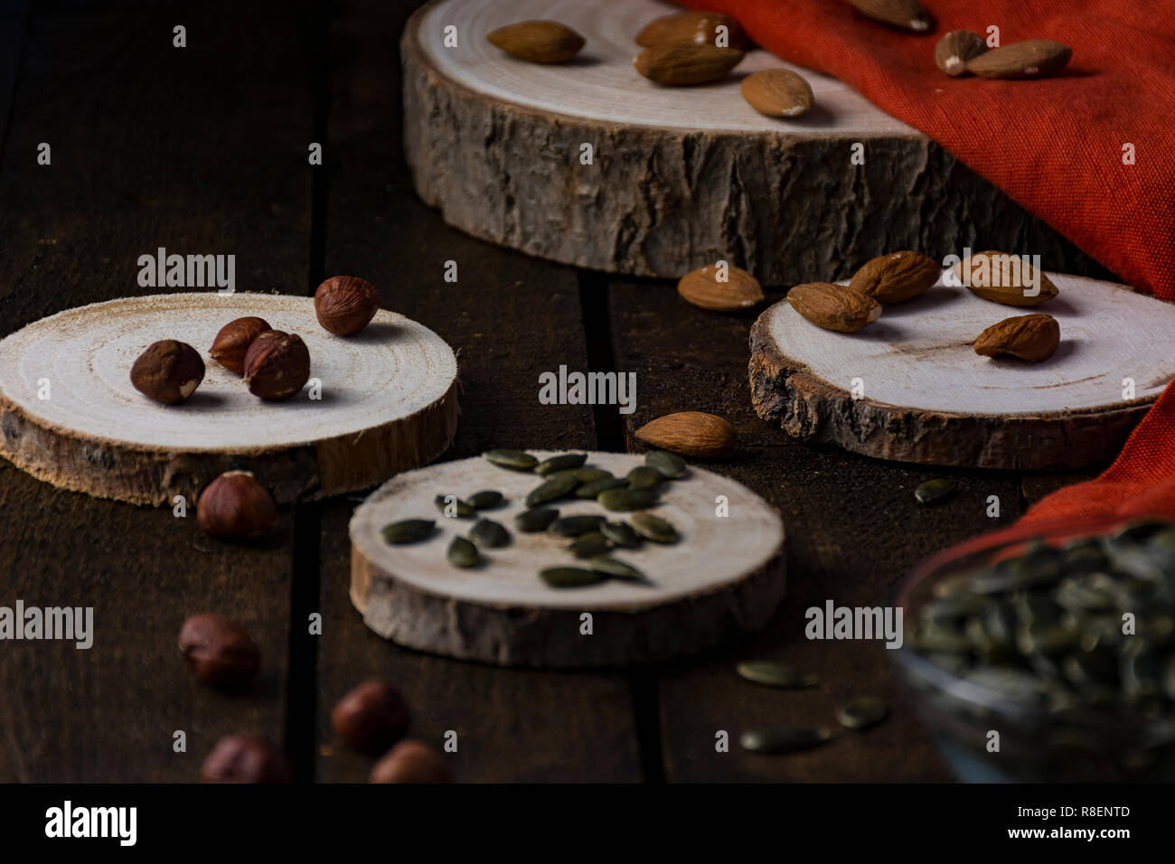 Mandorle, nocciole e semi di zucca a pezzi di registri e di un tessuto di colore arancione in stile scuro Foto Stock