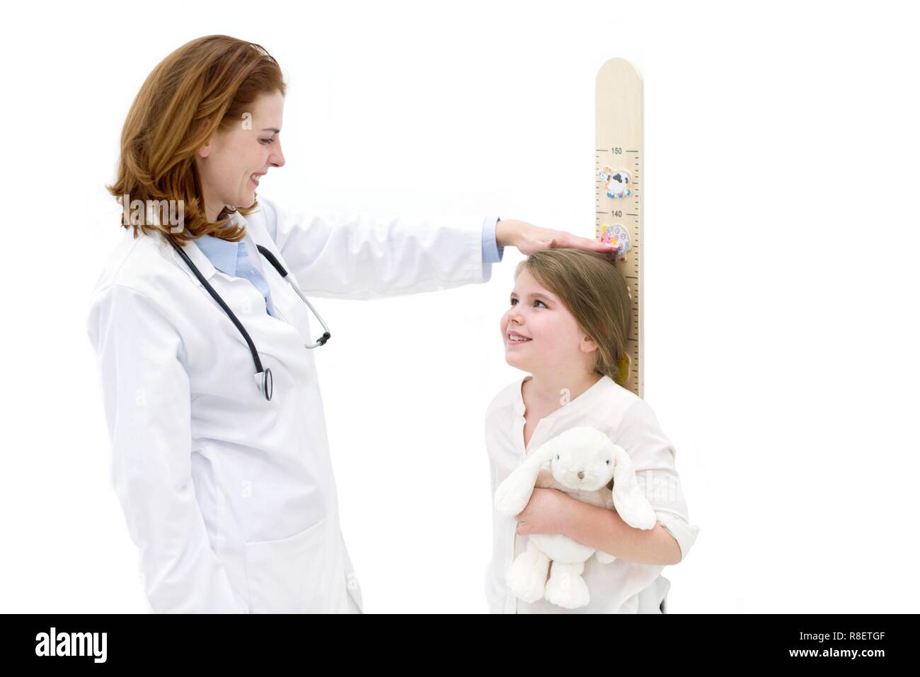Femmina misura medico giovane ragazza sul grafico di altezza. Foto Stock