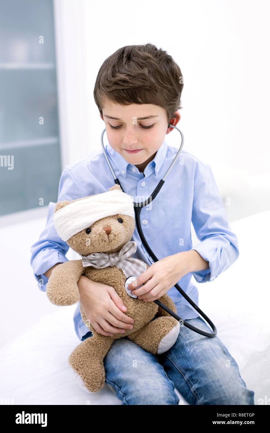 Ragazzo giochi di ruolo con Teddy bear e stetoscopio. Foto Stock