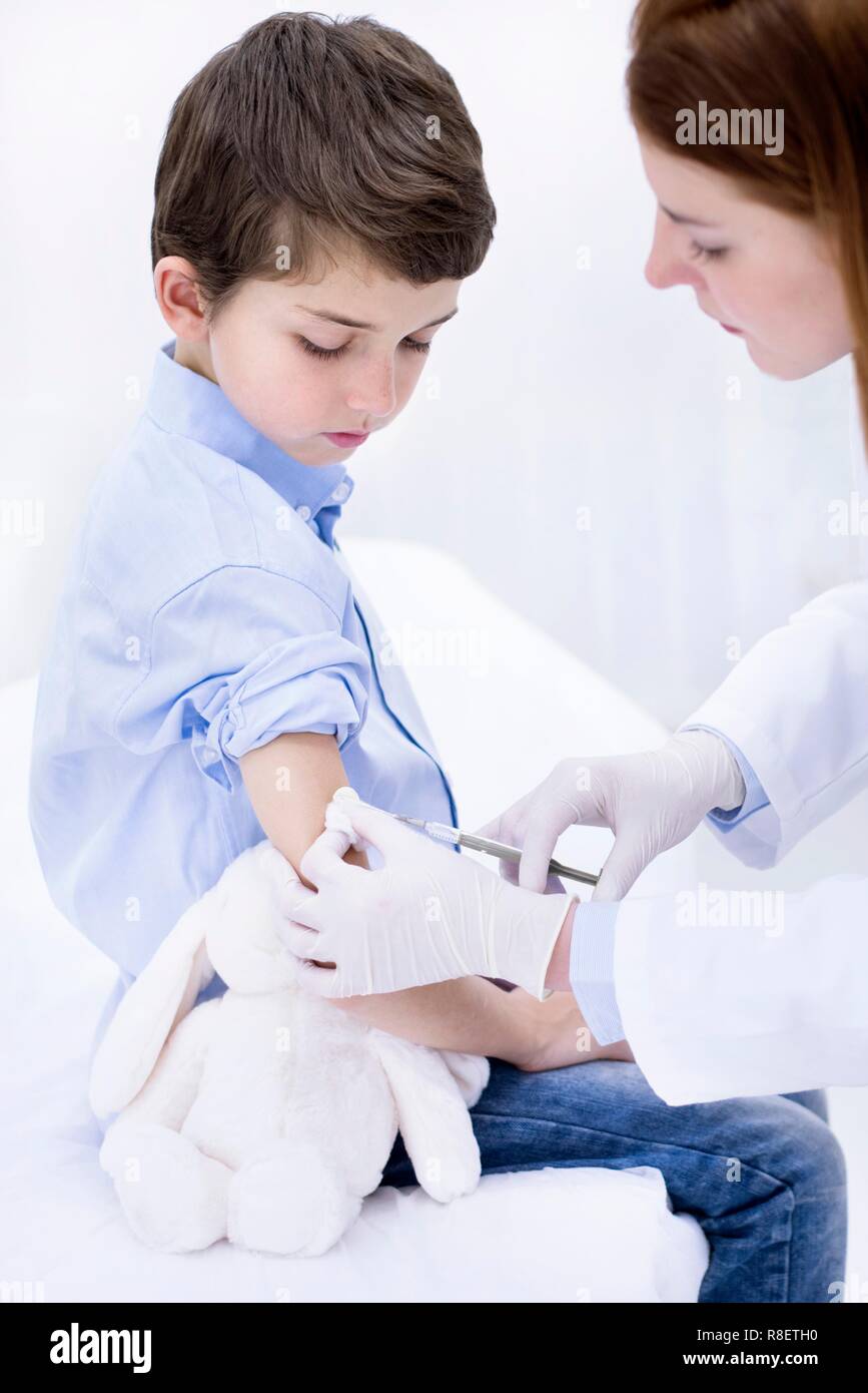 Medico dando boy iniezione nel braccio. Foto Stock