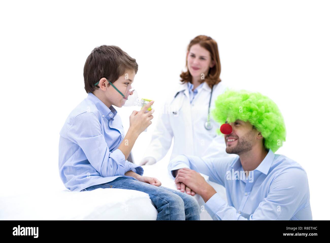 Ragazzo con ampolla con medico vestito come un clown. Foto Stock