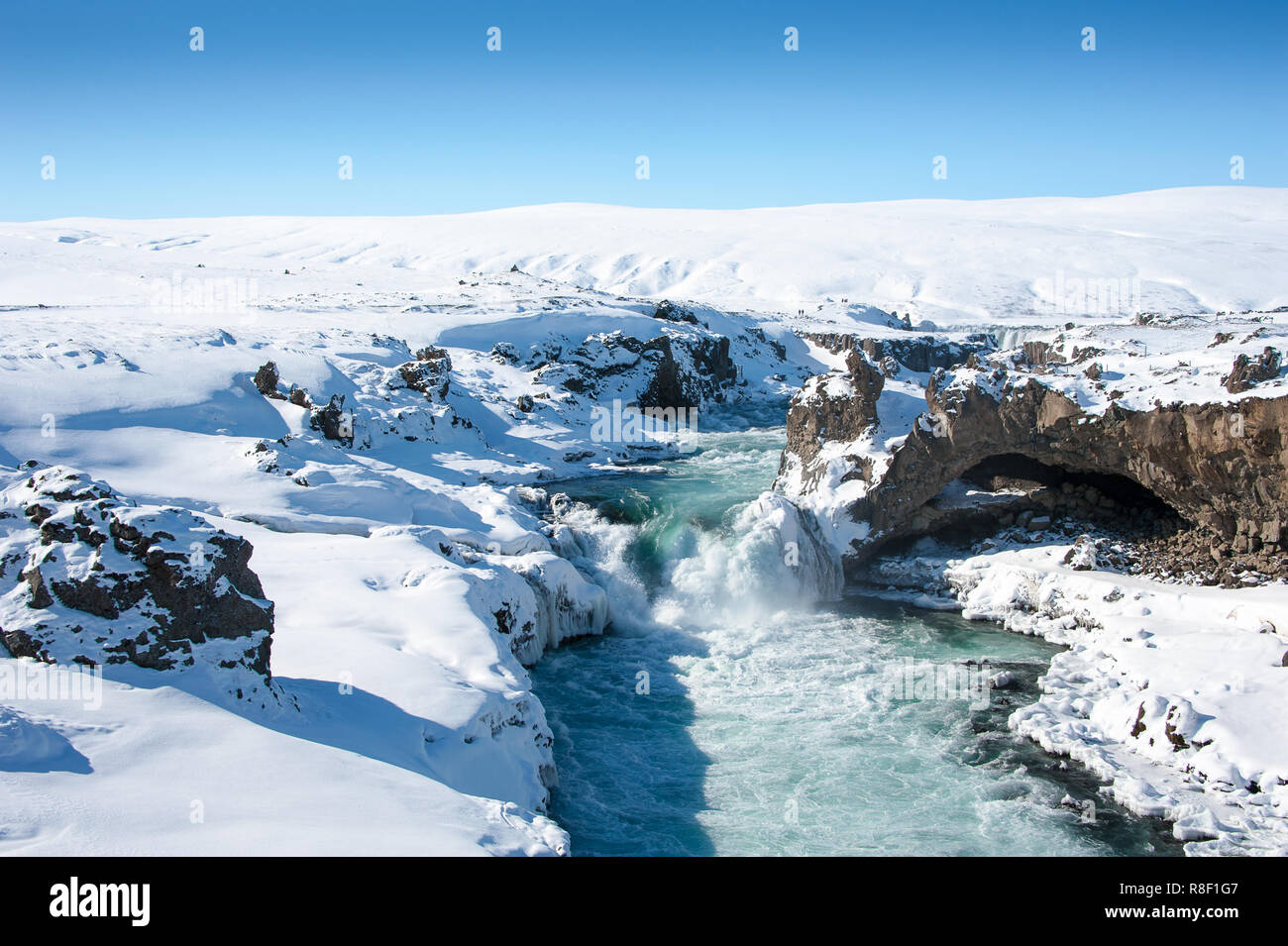 Acque selvagge di Skjalfandafljot fiume che scorre nelle cascate Godafoss. Agitando l'acqua turchese, innevato paesaggio congelato, contesto roccioso Foto Stock