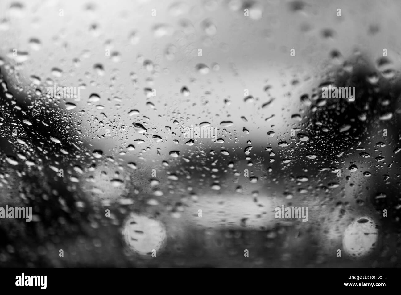 La pioggia caduta sul vetro auto sfondo.Vista su strada attraverso la finestra auto con gocce di pioggia, la guida in caso di pioggia.Abstract il traffico nel giorno di pioggia. Vista dal mare per auto Foto Stock