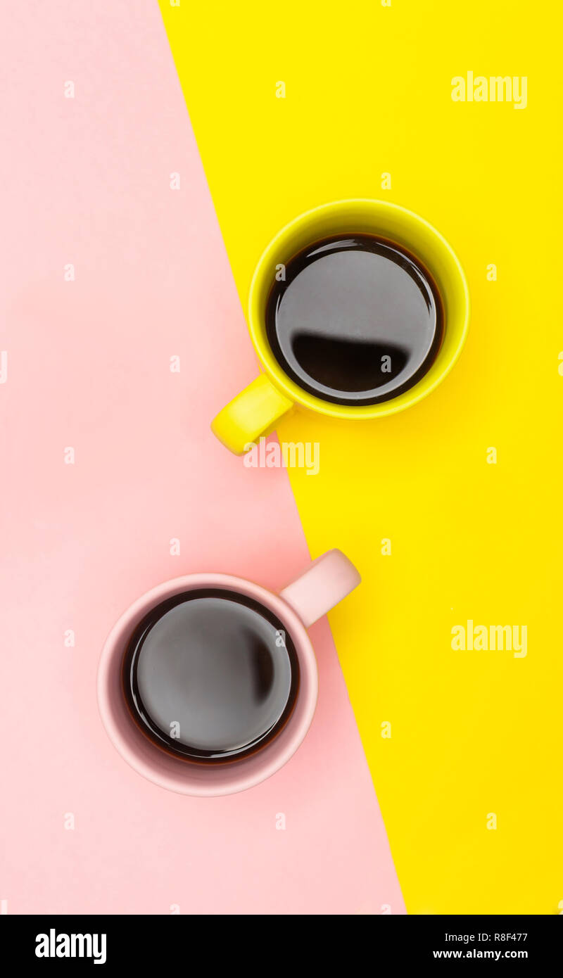 Lay piatto vista dall'alto di due tazze da caffè con rosa e giallo. Foto Stock