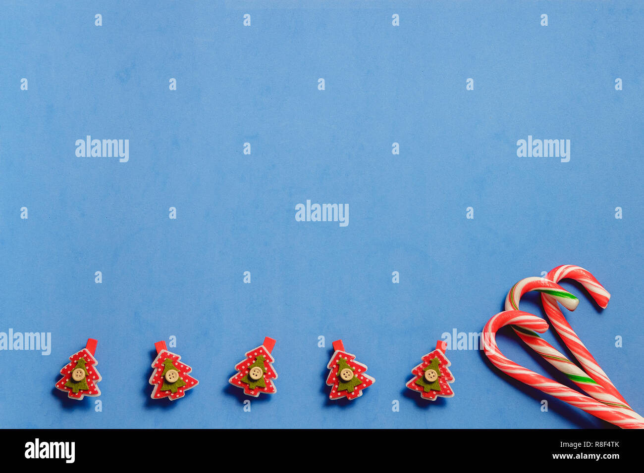 Vista superiore tre candy canne e cinque red fir tree shaptd pin su sfondo blu. Foto Stock