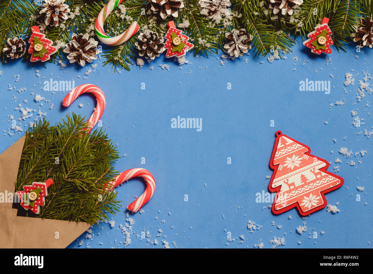 Vista superiore candy canes e abete rosso a forma di albero di perni in marrone craft busta su sfondo blu. Foto Stock