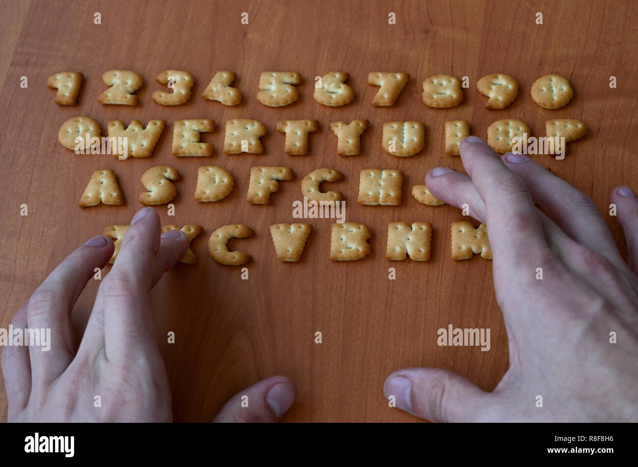 Gli uomini le dita per digitare sulla tastiera, che è composto di cracker salato in forma di lettere e numeri. La simulazione di una tastiera di computer utilizzando di c Foto Stock