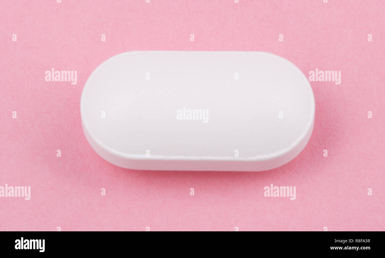 Pillola bianco su sfondo rosa Foto Stock