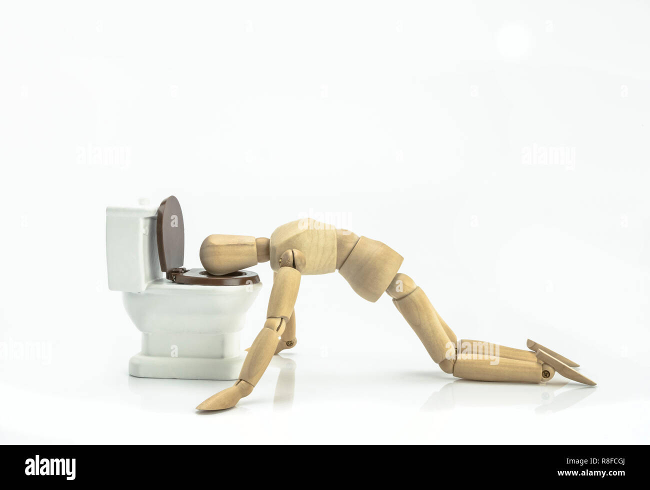 Legno bambola vomita in un wc isolato su sfondo bianco Foto Stock