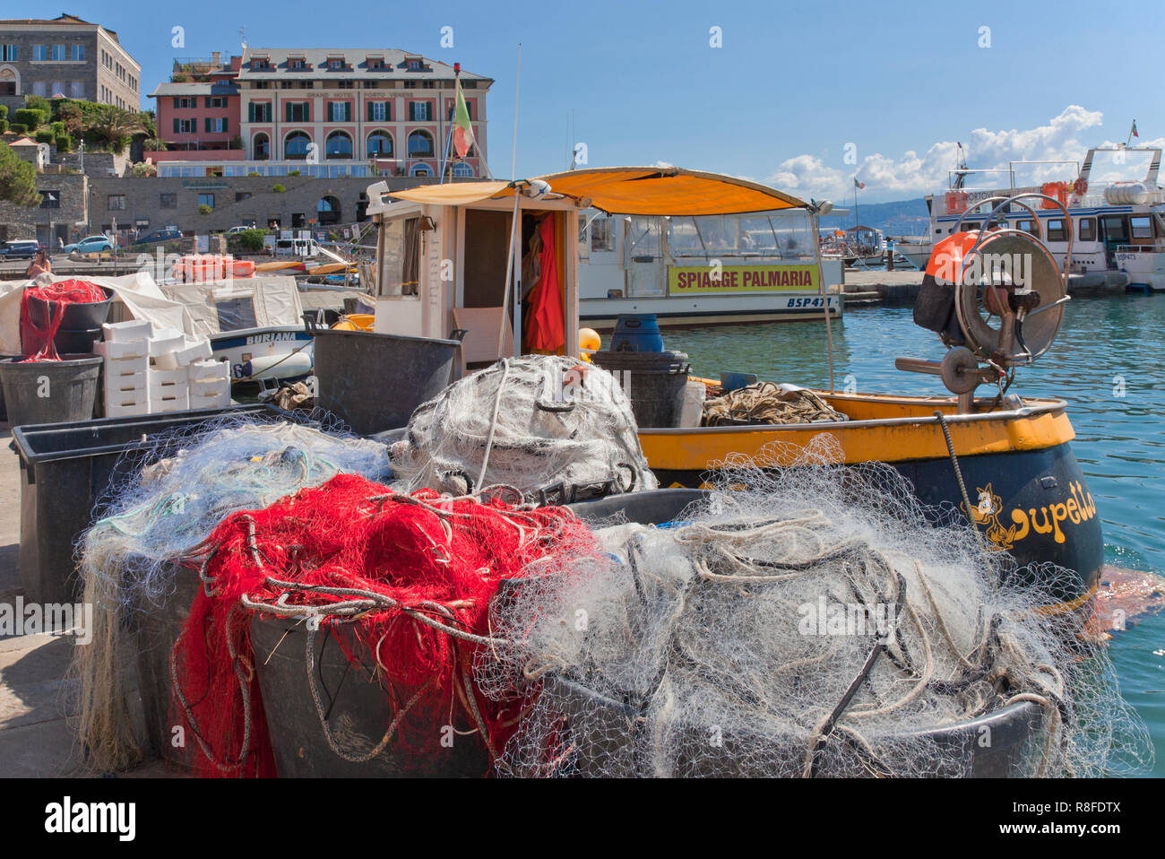 Barche e reti da pesca, via calata Doria, Portovenere, Italia. Segno sulla barca in background pubblicizza gite alle spiagge dell'isola di Palmeria. Foto Stock