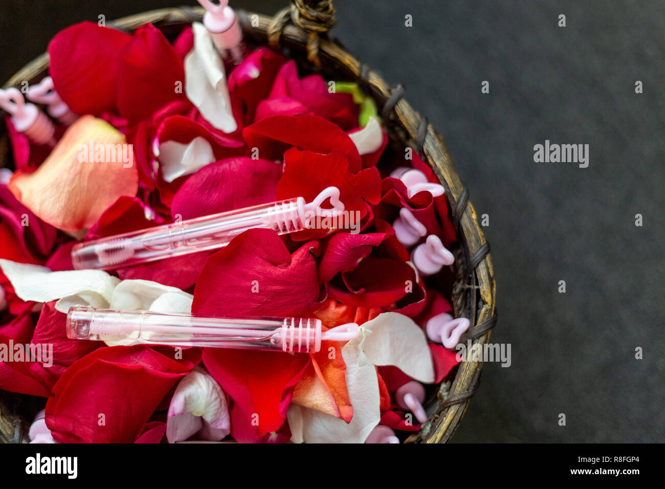 Decorazione per un matrimonio di un cesto in vimini con bolle e petali di rosa Foto Stock