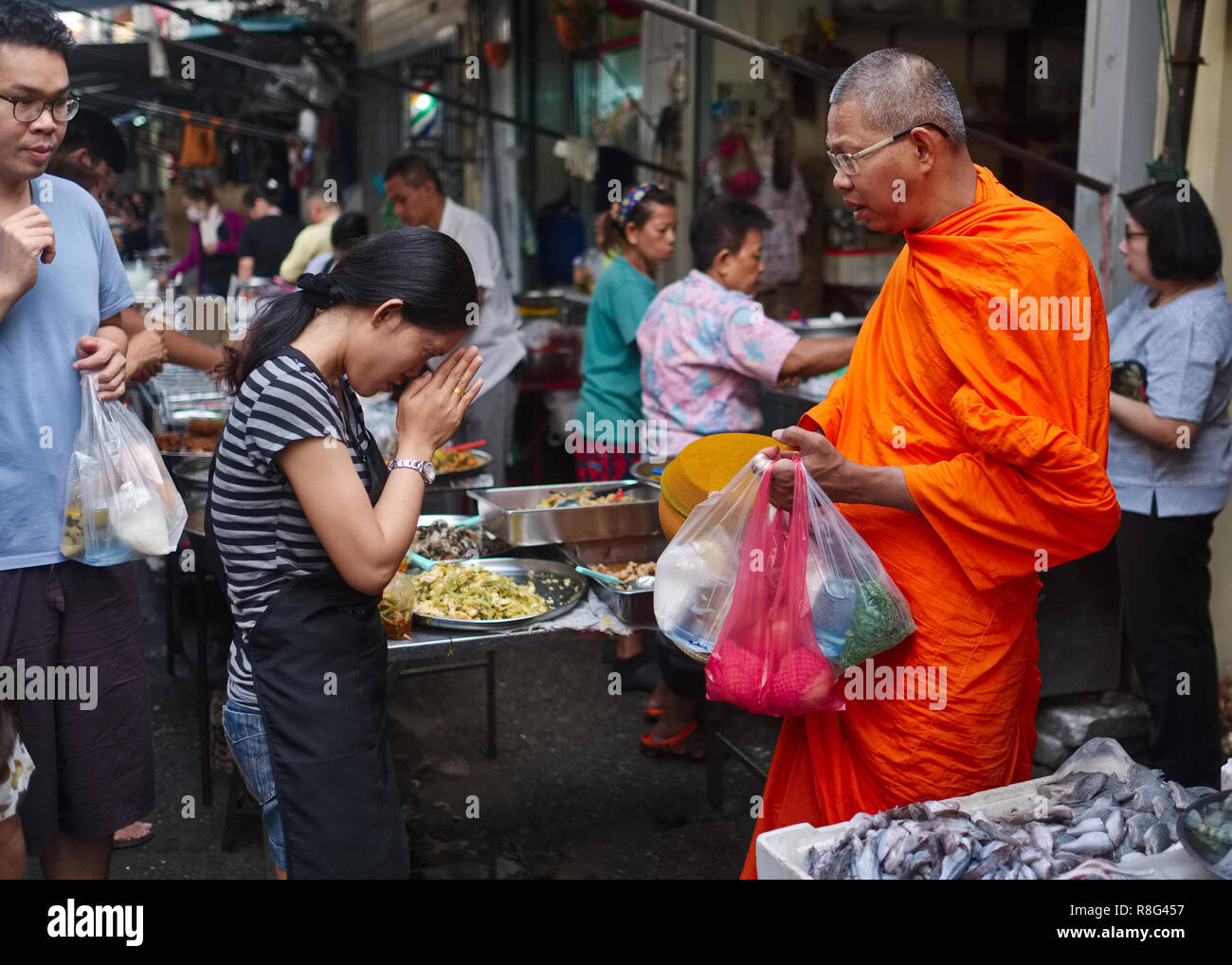Un monaco buddista in un mercato di strada a Bangkok, Thailandia, essendo onorato con un consueto Wai, un deferente saluto tailandese o gesto di rispetto Foto Stock
