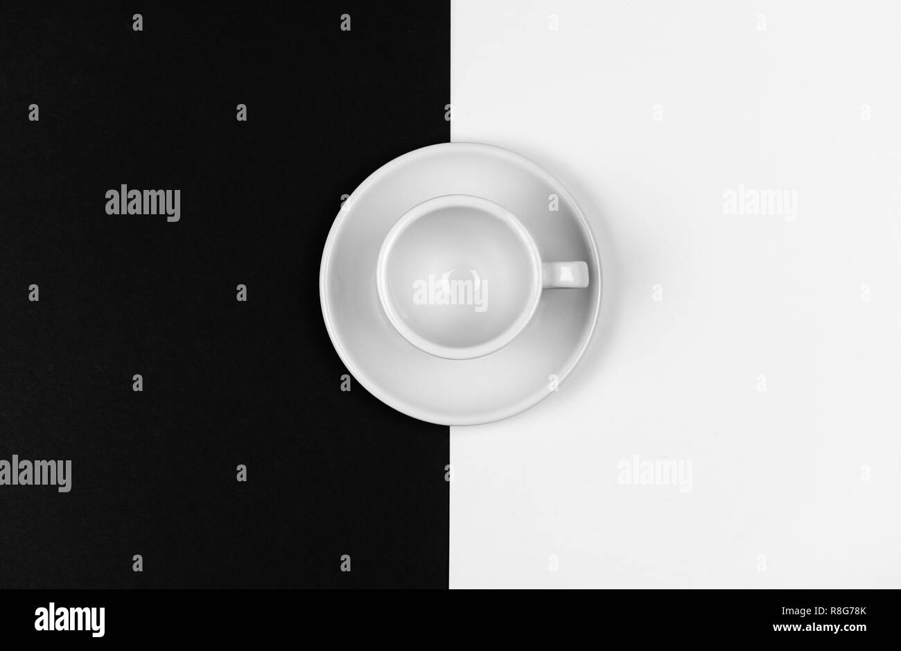 Vuoto bianco tazza da caffè in appoggio su un nero e sfondo bianco Foto Stock