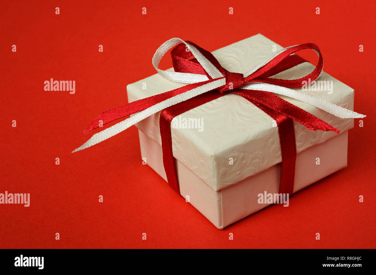 Confezione regalo con un inchino su sfondo rosso Foto Stock
