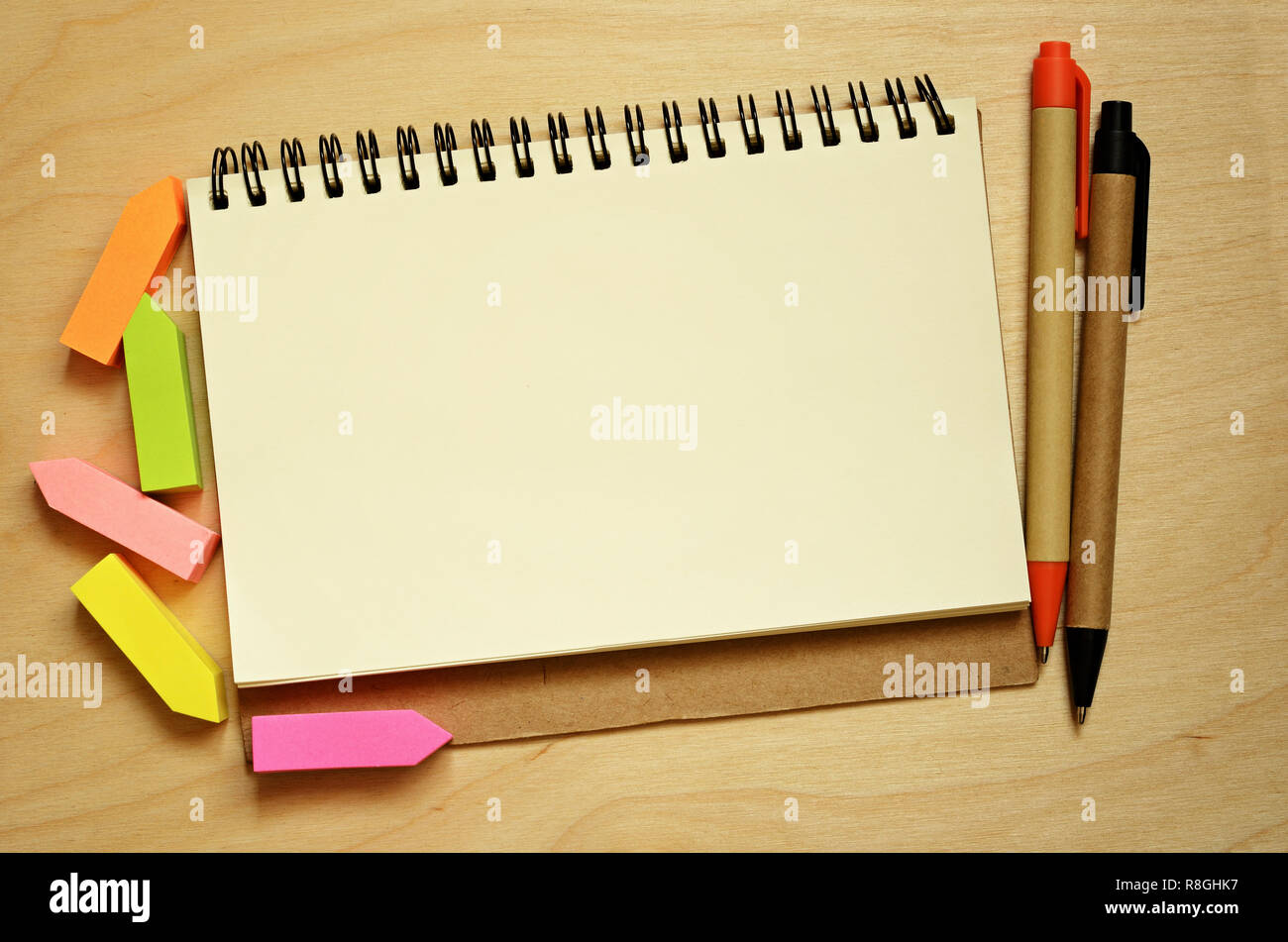 Notebook, adesivi e penne sulla scrivania in legno Foto Stock