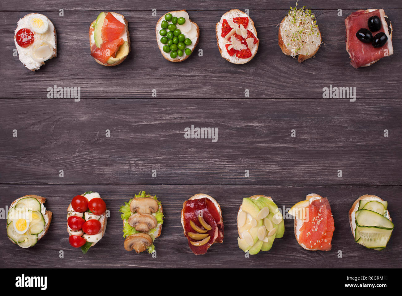 Crostini vari preparati con diversi ripieni di salmone, cetriolo, pomodoro ciliegino, mozzarella, uova, funghi, olive, avocado, mandorle. Foto Stock