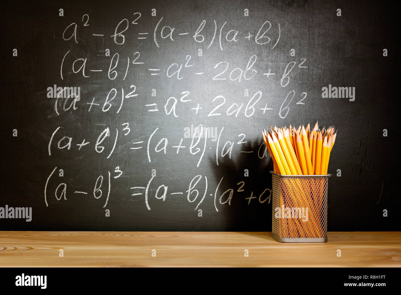 Matite in legno banco di scuola di fronte a una lavagna nera con formule matematiche scuola. Il concetto di istruzione - la scrivania in auditorium Foto Stock