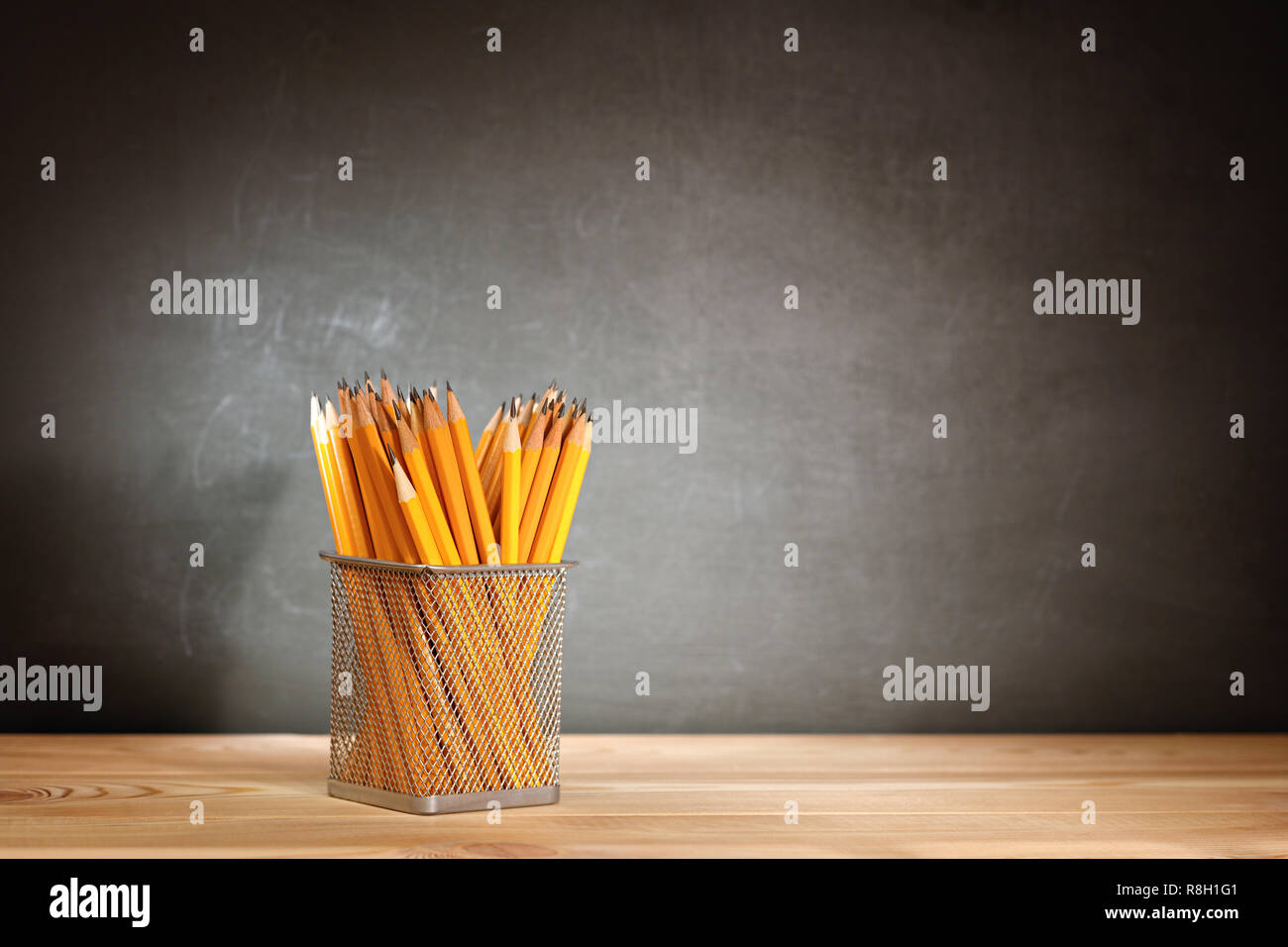 Matite in legno banco di scuola di fronte a una lavagna scuola. Il concetto di istruzione - la scrivania in auditorium Foto Stock