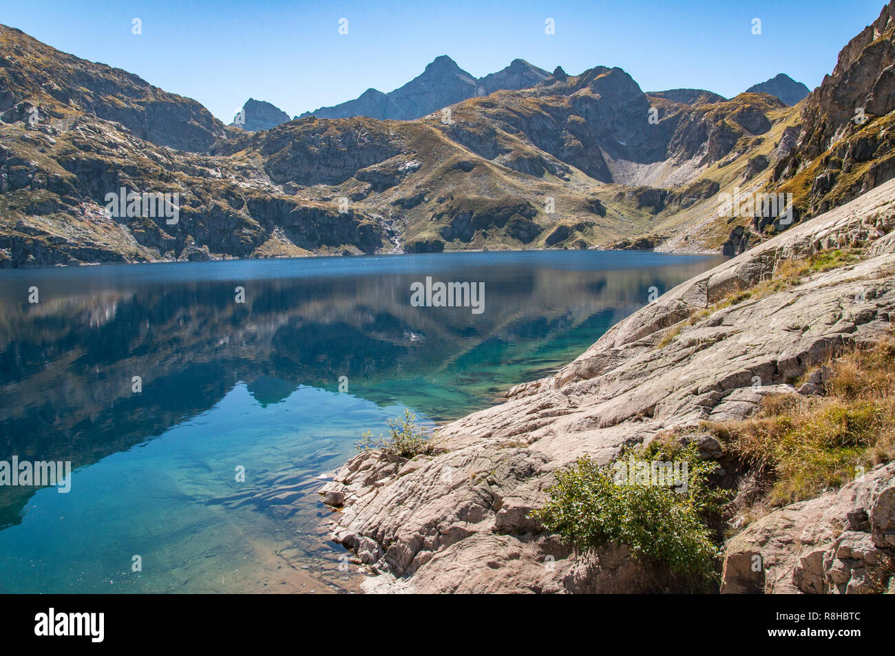 Le rive del Lac d'Artouste in francese Pirenei su una tranquilla giornata autunnale con le montagne che si riflettono nell'acqua Foto Stock