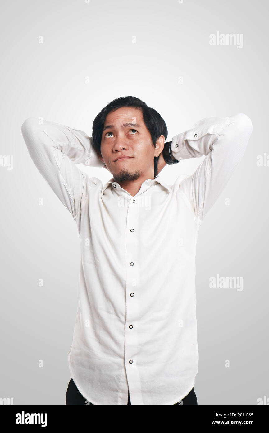 Foto immagine ritratto di un divertente giovane imprenditore asiatico cercando felice e sorridente mentre pensando a qualcosa, close up ritratto, permanente gestu relax Foto Stock
