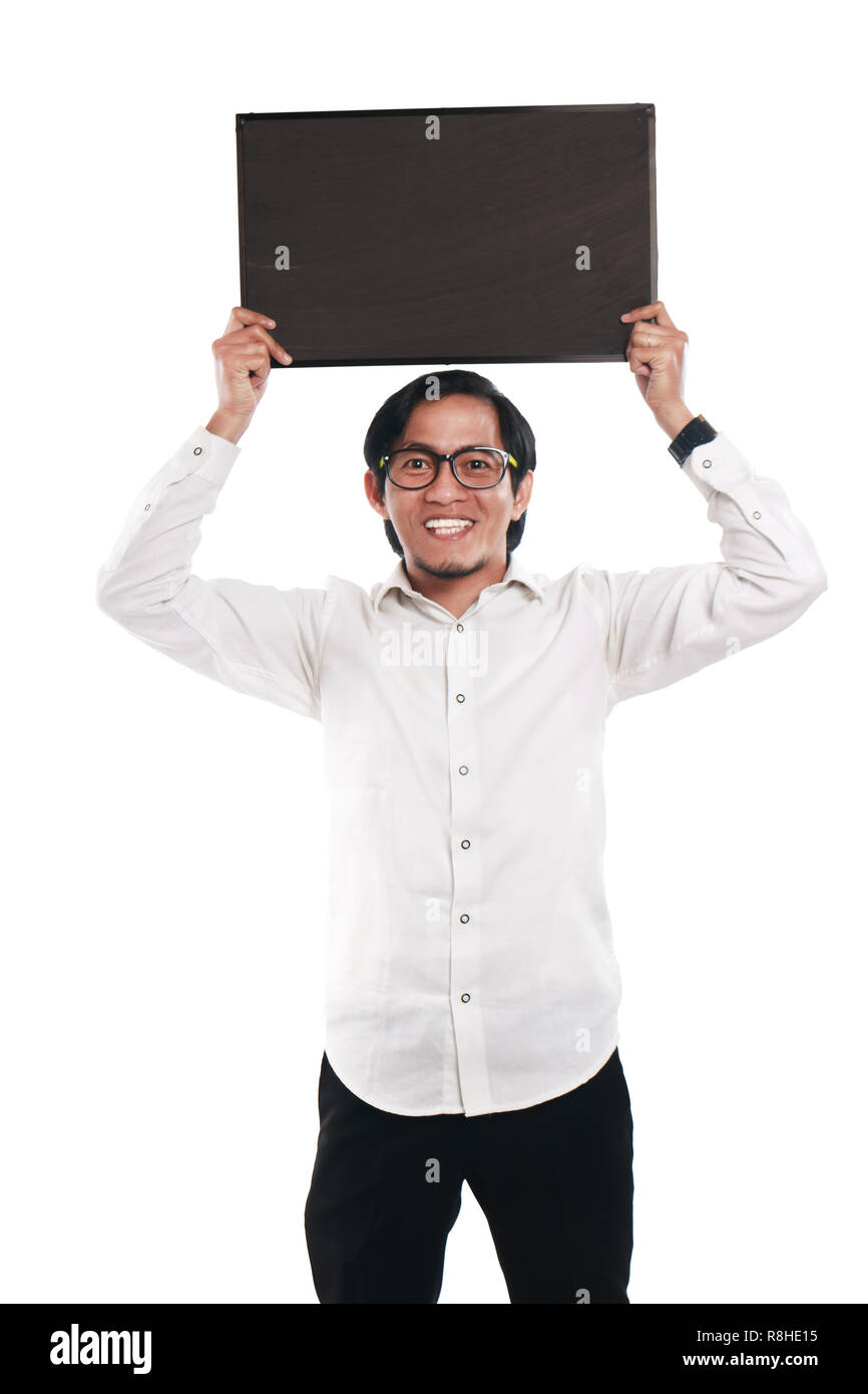 Foto immagine ritratto di funny Asian imprenditore o un insegnante o studente mostrando lavagna vuota con volto sorridente, tenendo blackboard sopra la sua testa, ov Foto Stock