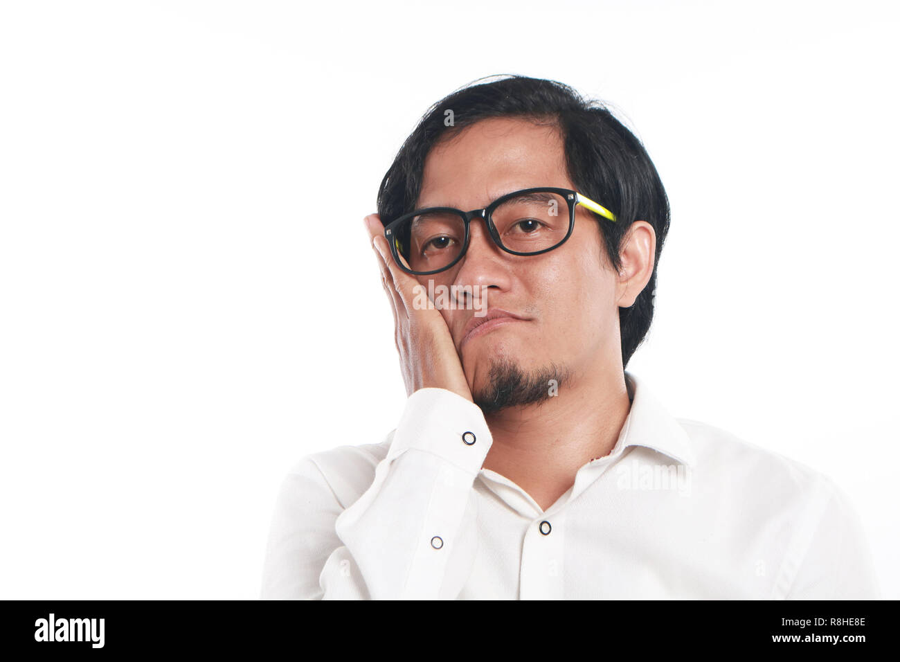 Foto immagine ritratto di un divertente giovane imprenditore asiatica con gli occhiali sembrava molto annoiato o avere mal di denti, close up verticale che mostra il volto triste e con Foto Stock
