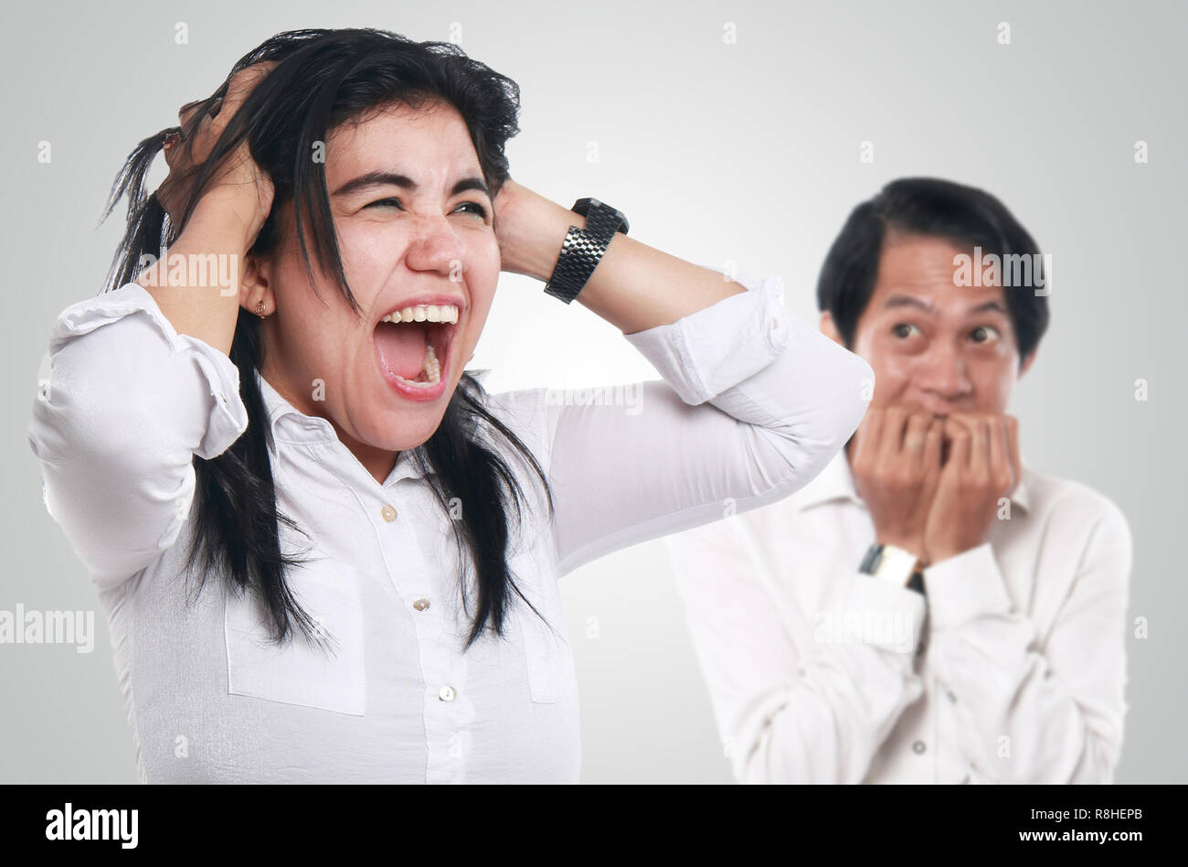 Immagine fotografica di un pazzo Asian imprenditrice urlando mentre una paura uomo sembrava preoccupata in background, crazy giovane concetto Foto Stock