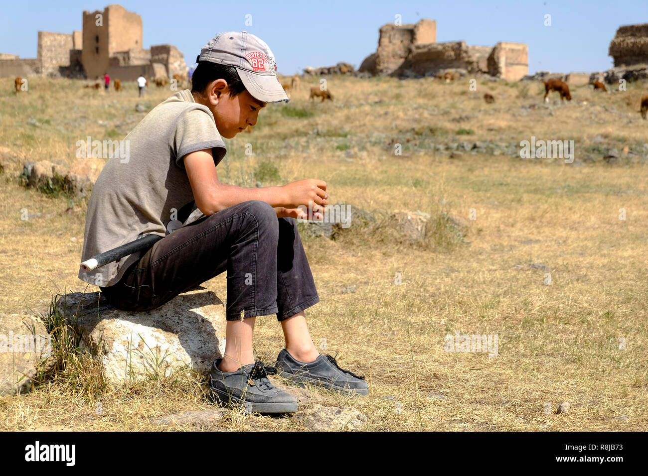 Pastore kid in attesa per le vacche a pascolare Foto Stock