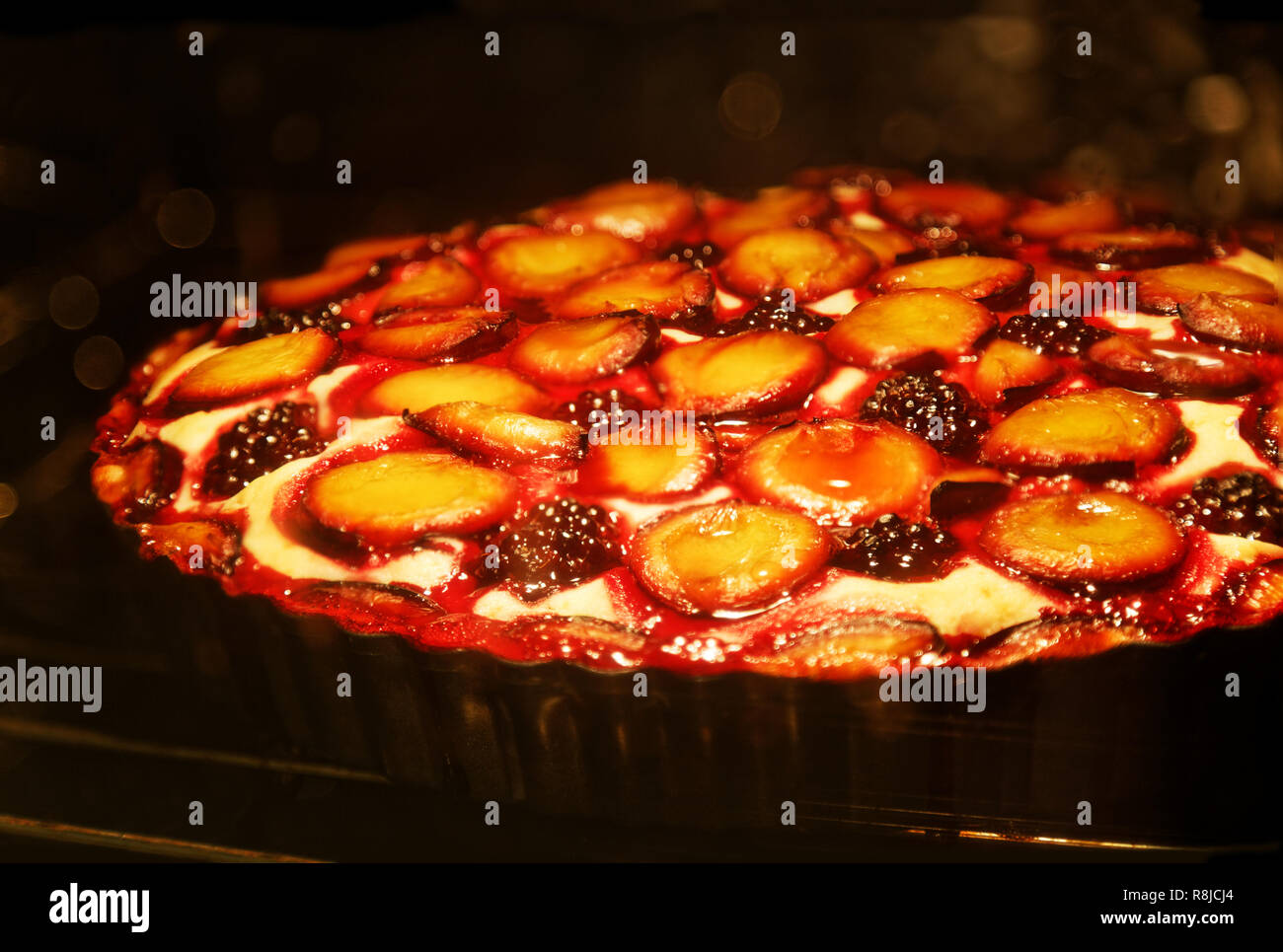 Primo Piano in casa berry torta con prugne e blackberry viene cotta in forno. Messa a fuoco poco profonde. Foto Stock