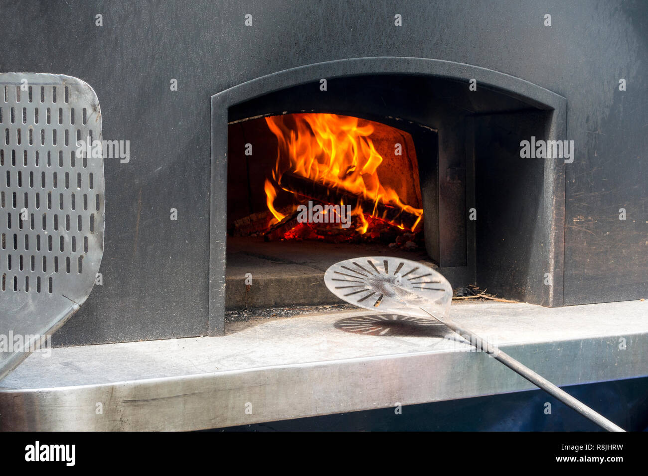 Commerciale moderno in acciaio di grado forno a legna e cucina italiana tradizionale con cupola isolata per la ritenzione del calore con il metallo delle pale per pizza Foto Stock