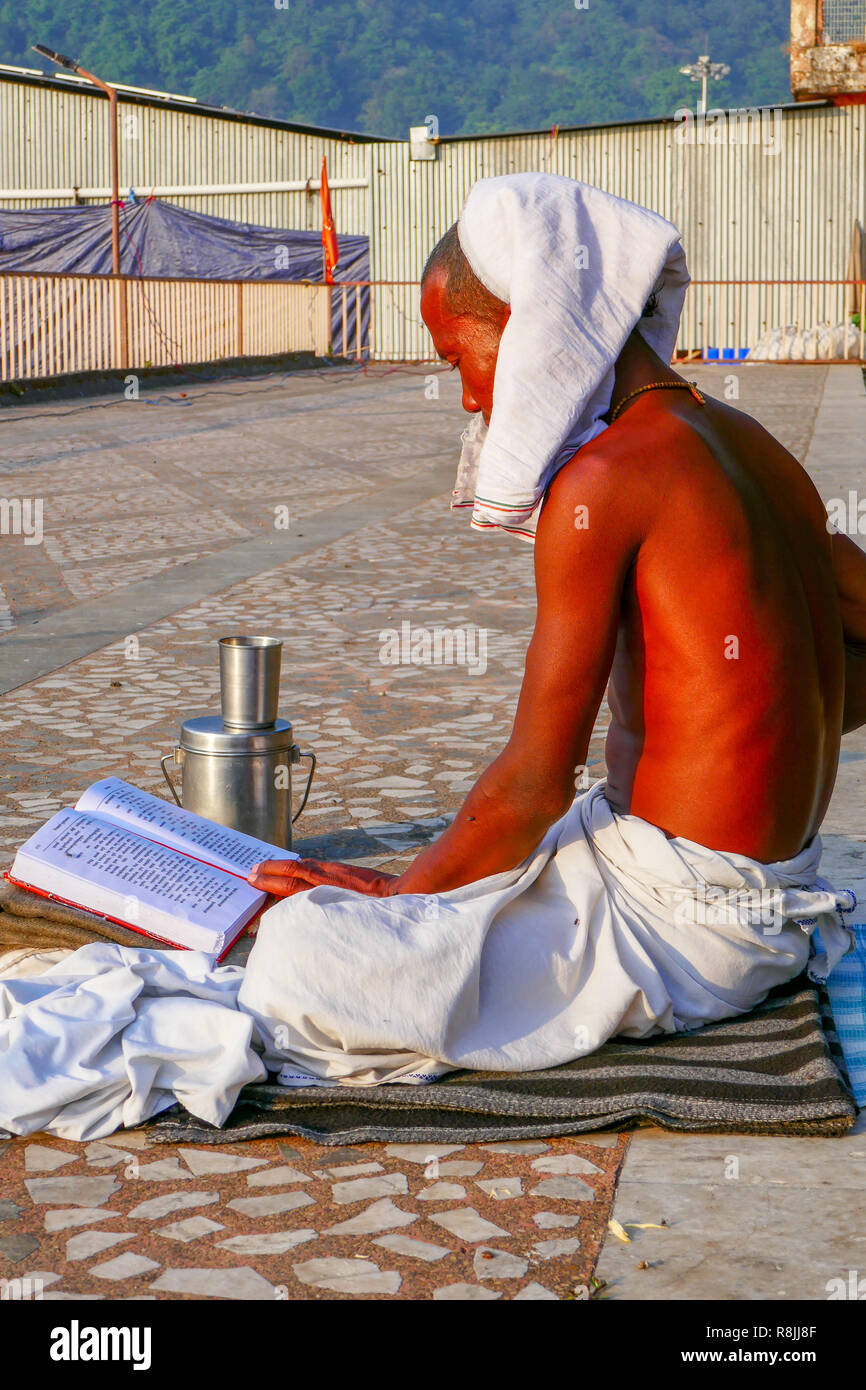 Yogi seduto sul marciapiede e la lettura a Rishikesh, India Foto Stock