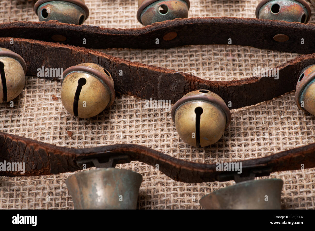 Antique vintage ossidare ottone sleigh bells sul cinturino in pelle e tela sfondo Foto Stock