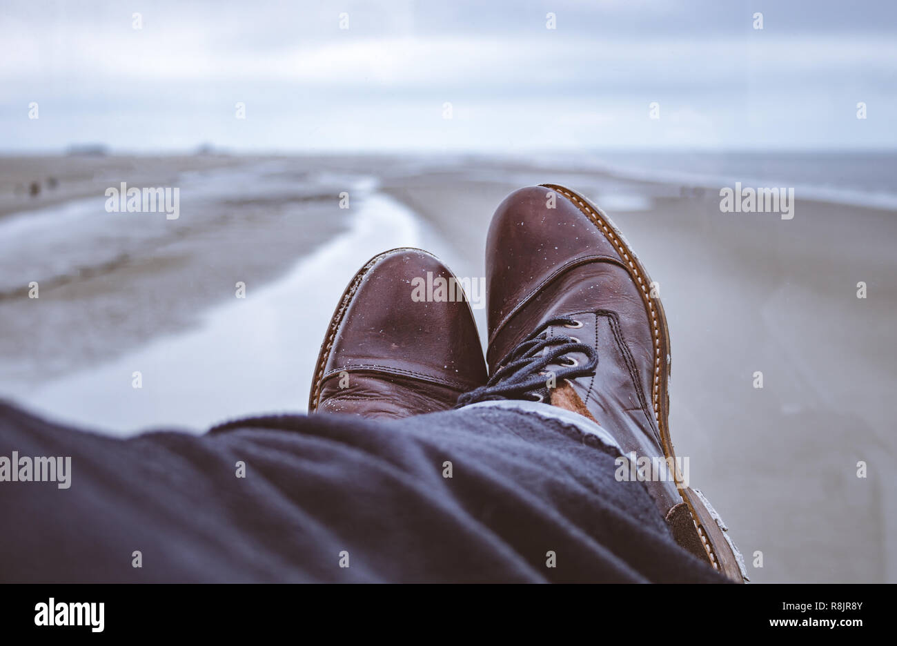 Primo piano di stivali in pelle sotto coperte di lana con una splendida vista a mare del Nord spiaggia. Foto Stock