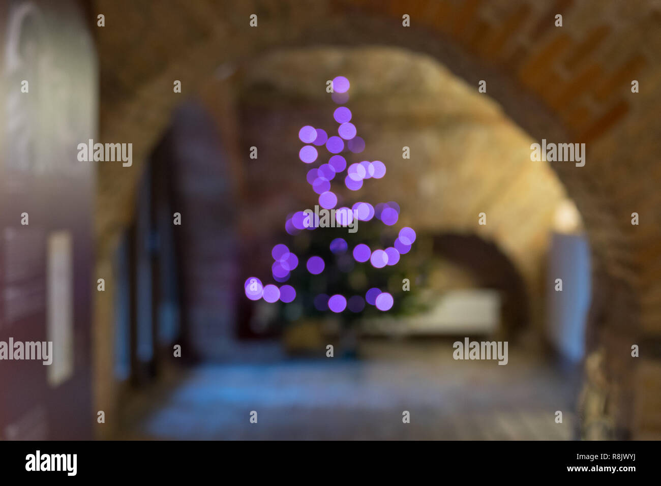 Defocalizzata albero di Natale silhouette nella vecchia sala festosa e viola bokeh illuminazione, sfocate sullo sfondo di vacanza Foto Stock