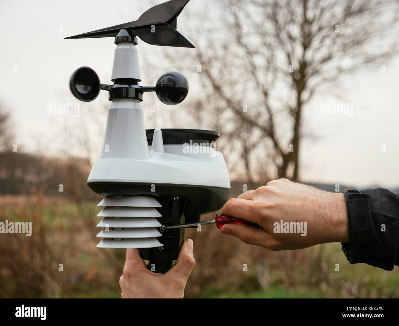 Uomo di installare una stazione meteorologica personale su un palo in una fattoria in Germania. Foto Stock