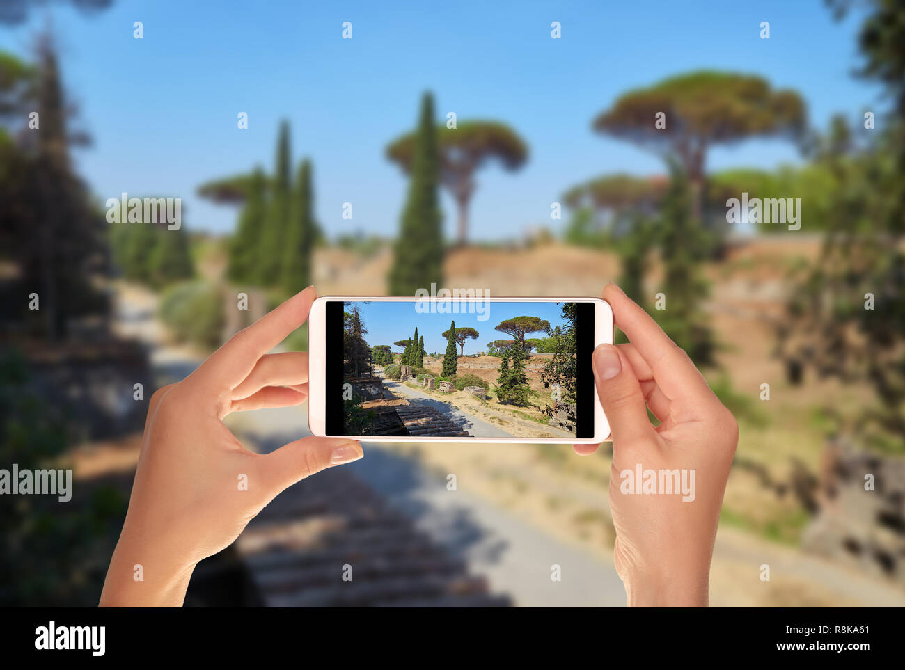Un turista è scattare una foto della strada tra le rovine di Pompei su un estate giornata di sole su un telefono cellulare Foto Stock