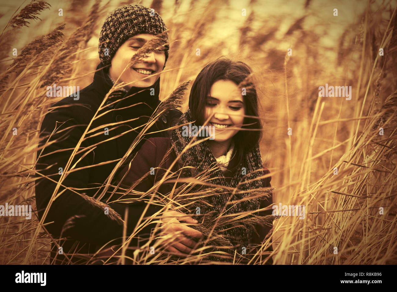 Felice coppia giovane a piedi nella boscaglia di giunco moda uomo e donna che indossa cappotto classico e beanie Foto Stock