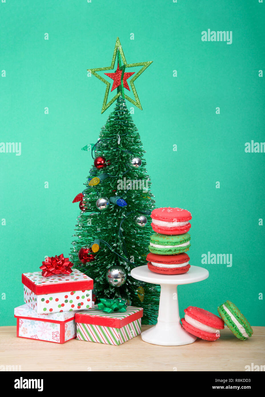 Vacanze di Natale style macaron cookies impilati su un piedistallo e posa sul tavolo di legno con luce verde con sfondo colorato e presenta piccole ch Foto Stock