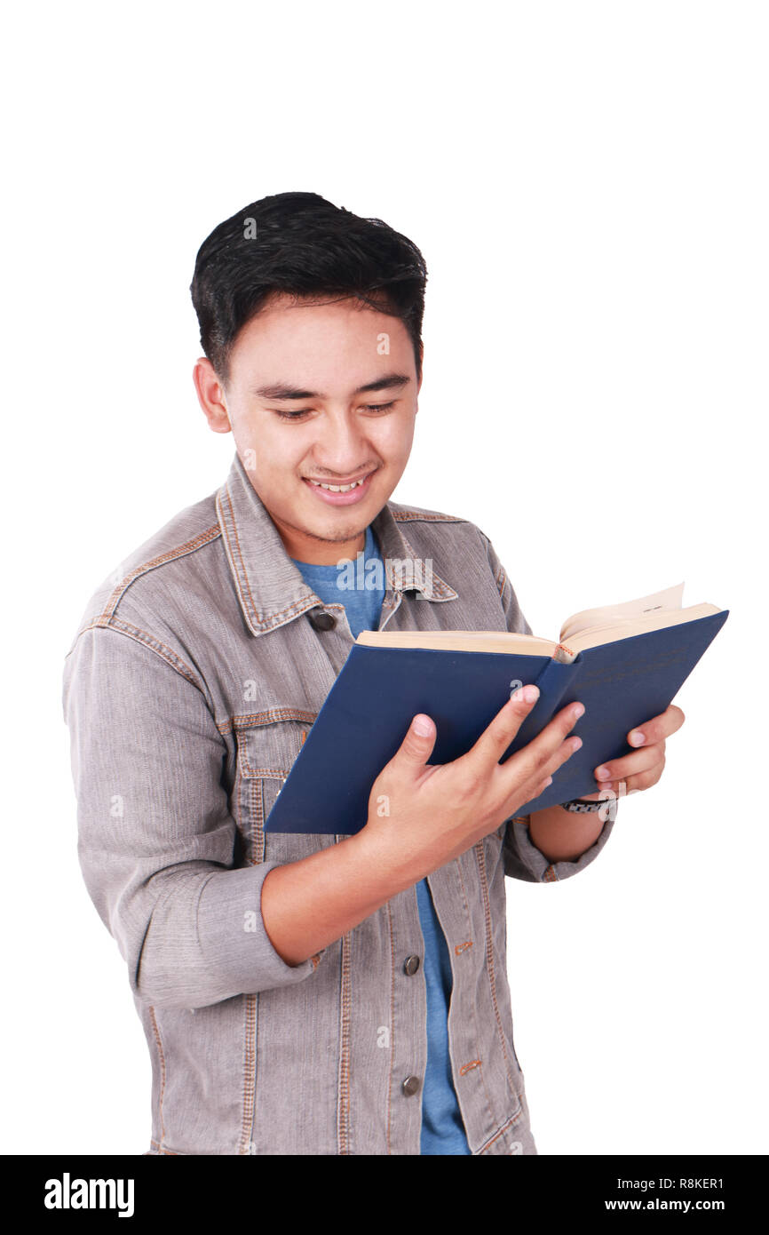 Foto immagine ritratto di un simpatico giovani asiatici studente maschio in piedi e sorridente durante la lettura di un libro, isolato su bianco Foto Stock