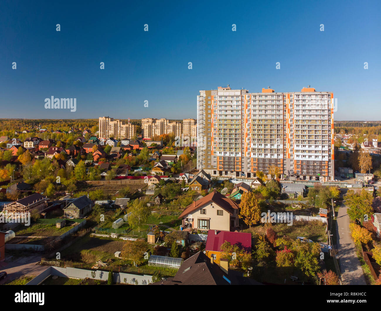Alto edificio residenziale in costruzione tra case private in Russia Foto Stock