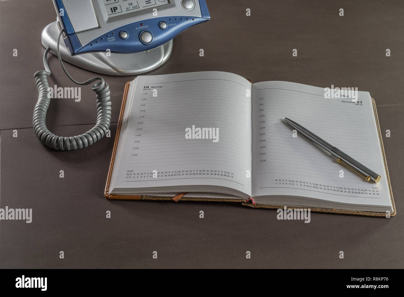 Un telefono su una scrivania in ufficio con una calandra libro. il calendario Foto Stock