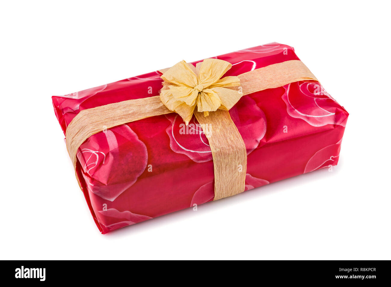 Confezione regalo avvolto in una rosa rossa cellophane, decorata con rafia ecru nastro e bow isolati su sfondo bianco Foto Stock